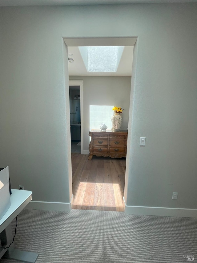 hall featuring light wood-type flooring and a skylight