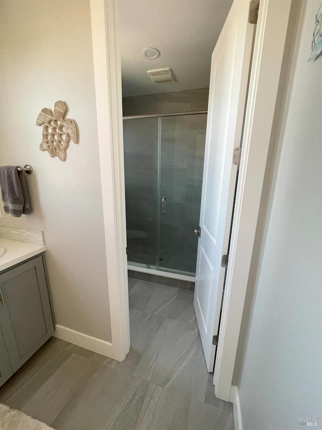 bathroom featuring a shower with door and vanity