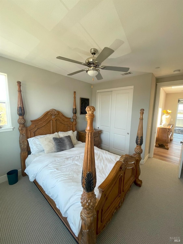 carpeted bedroom with ceiling fan, a closet, and multiple windows