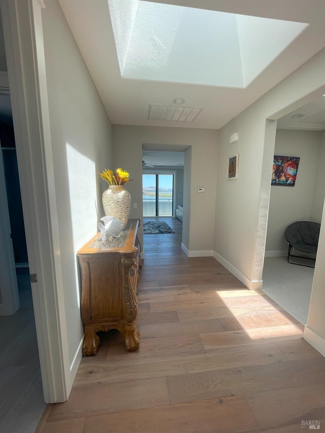 hallway with a skylight and light wood-type flooring