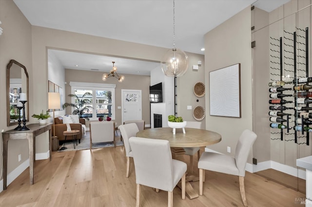 dining room featuring a fireplace, light hardwood / wood-style floors, and an inviting chandelier