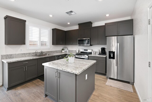 kitchen featuring stainless steel appliances, sink, a kitchen island, and light wood-type flooring