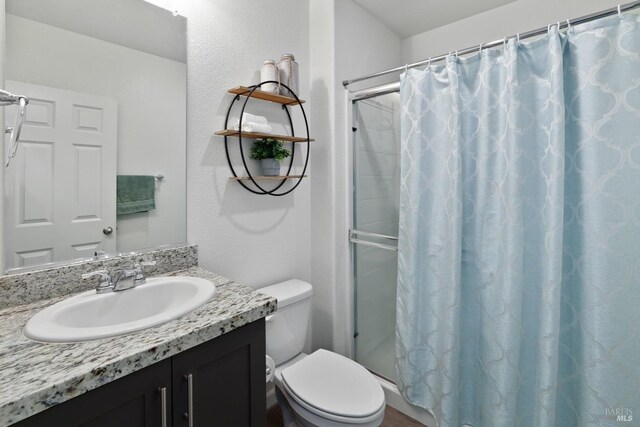 bathroom featuring toilet, vanity, and walk in shower