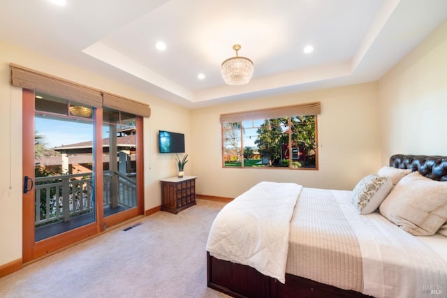 carpeted bedroom featuring multiple windows, access to exterior, and a tray ceiling