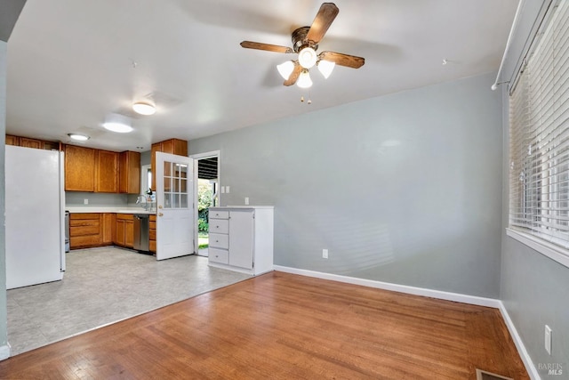 kitchen with stainless steel dishwasher, light hardwood / wood-style floors, a wealth of natural light, and white fridge