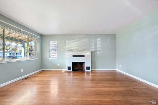 unfurnished living room with wood-type flooring and a brick fireplace