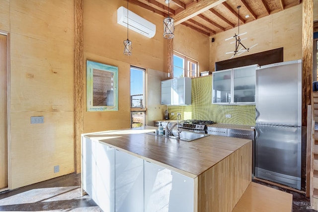 kitchen featuring beamed ceiling, sink, backsplash, hanging light fixtures, and stainless steel refrigerator