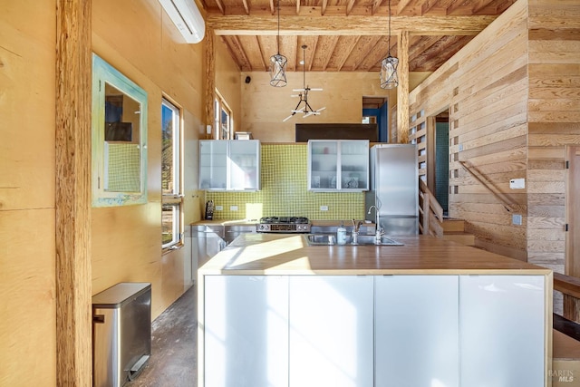 kitchen featuring pendant lighting, beam ceiling, a center island with sink, stainless steel refrigerator, and wood ceiling