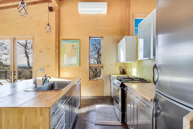 kitchen with pendant lighting, sink, a wall mounted air conditioner, stainless steel appliances, and wood counters