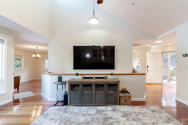 living room with high vaulted ceiling, a chandelier, and hardwood / wood-style floors