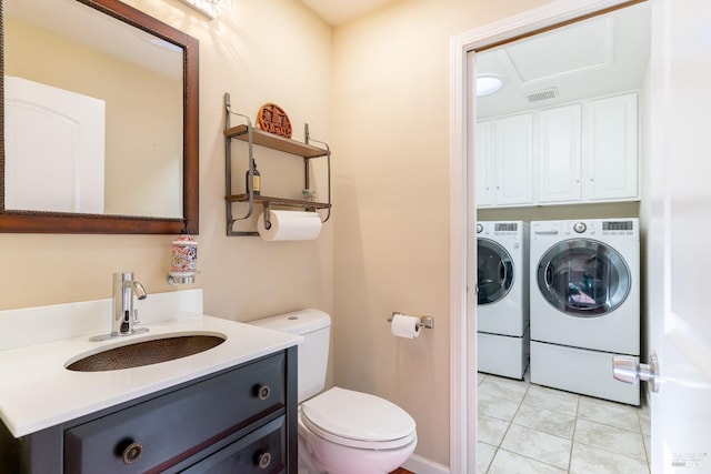 bathroom featuring tile patterned flooring, vanity, washer and dryer, and toilet