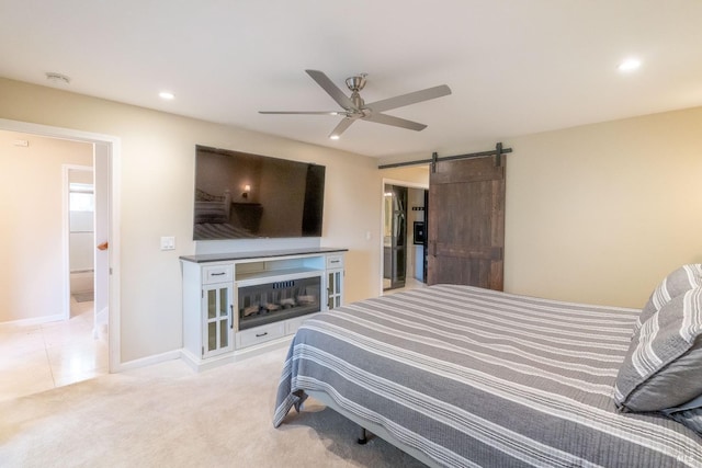 carpeted bedroom with a barn door and ceiling fan