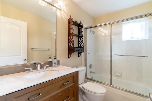 full bathroom featuring vanity, shower / bath combination with glass door, and toilet