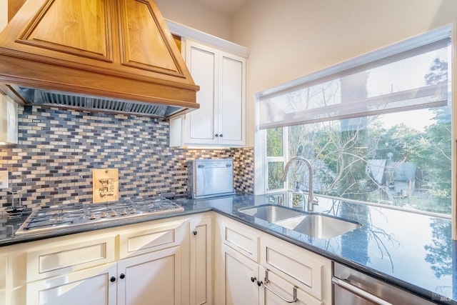 kitchen featuring sink, backsplash, appliances with stainless steel finishes, custom range hood, and white cabinets