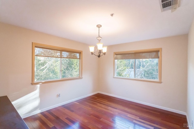 spare room featuring dark hardwood / wood-style floors and a notable chandelier