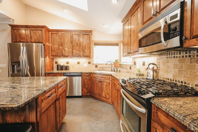 kitchen with lofted ceiling, sink, backsplash, stainless steel appliances, and light stone counters