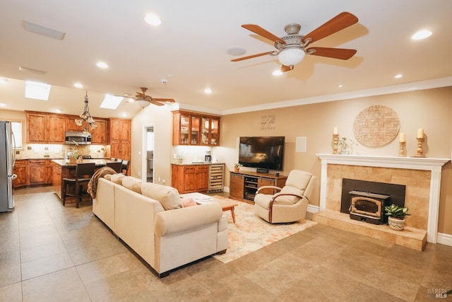 living room with ceiling fan, ornamental molding, and a skylight