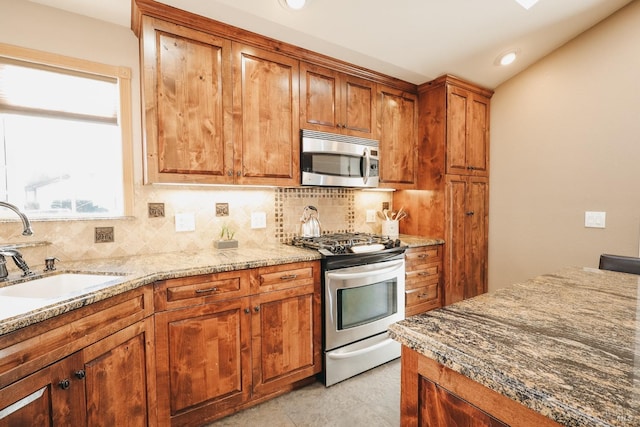 kitchen with lofted ceiling, sink, light stone counters, tasteful backsplash, and stainless steel appliances