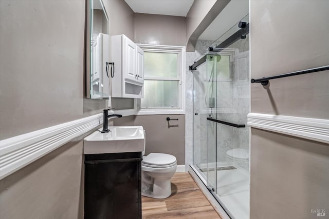 bathroom with vanity, wood-type flooring, a shower with shower door, and toilet