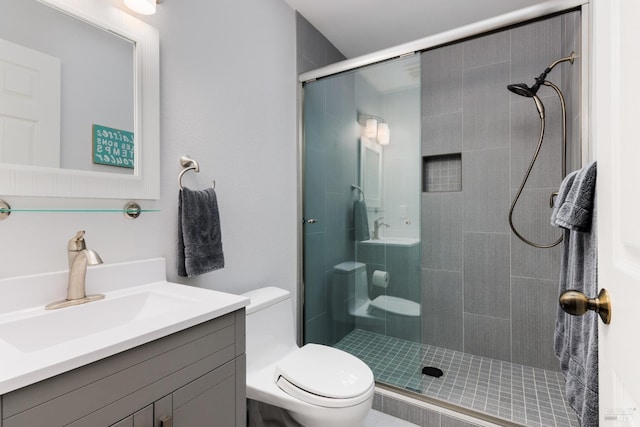 bathroom with toilet, a shower with door, and vanity