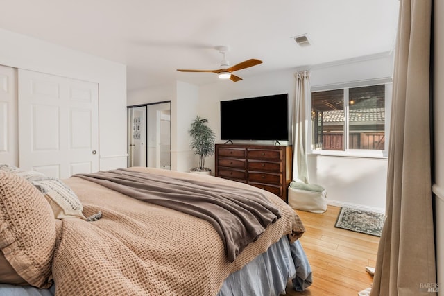 bedroom with ceiling fan, two closets, and hardwood / wood-style floors