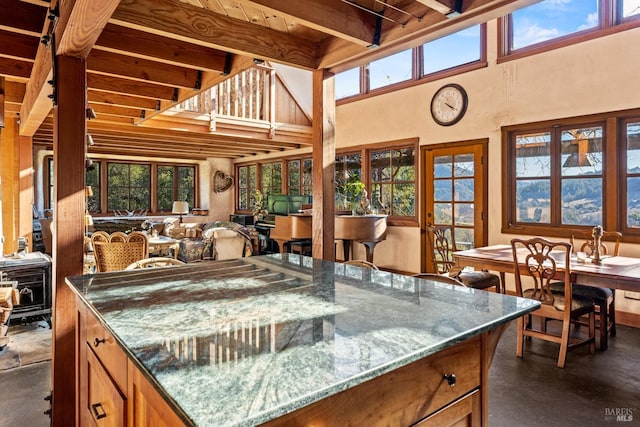 kitchen with a towering ceiling, stone counters, and beam ceiling