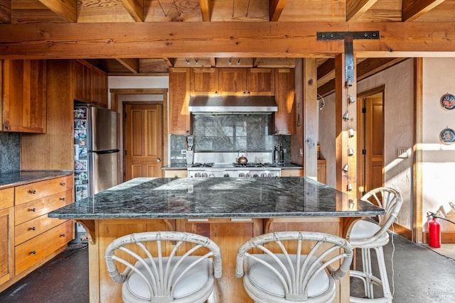 kitchen with a center island, beamed ceiling, a kitchen breakfast bar, backsplash, and stainless steel refrigerator