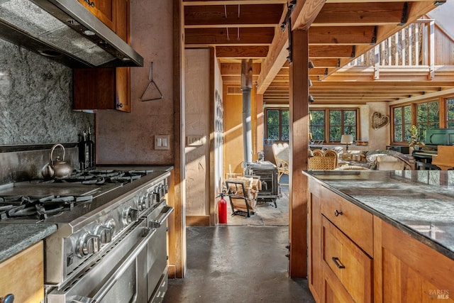 kitchen with range hood, range with two ovens, a wood stove, and dark stone countertops