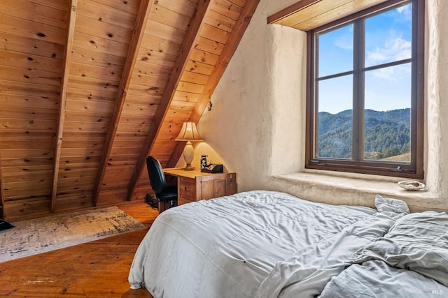 bedroom featuring a mountain view, hardwood / wood-style floors, lofted ceiling with beams, and wood ceiling