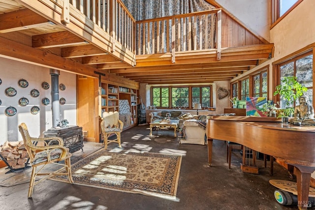 interior space with a wood stove, a healthy amount of sunlight, and a towering ceiling