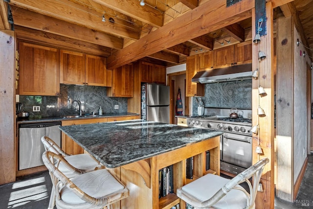 kitchen featuring appliances with stainless steel finishes, sink, tasteful backsplash, a kitchen island, and beamed ceiling