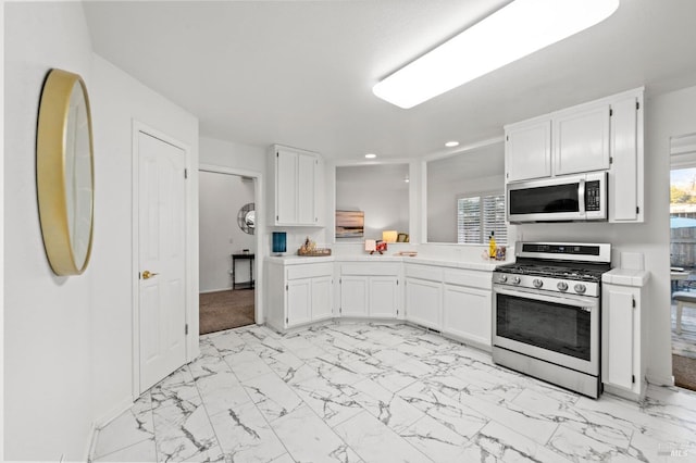 kitchen featuring white cabinets, stainless steel gas range, marble finish floor, and light countertops