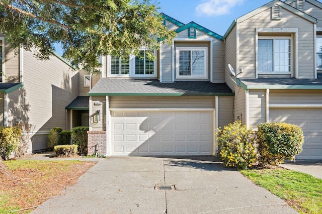 view of front of home featuring a garage, driveway, a shingled roof, and brick siding