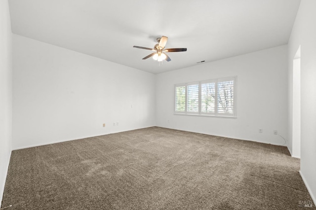 spare room featuring carpet floors, ceiling fan, and visible vents