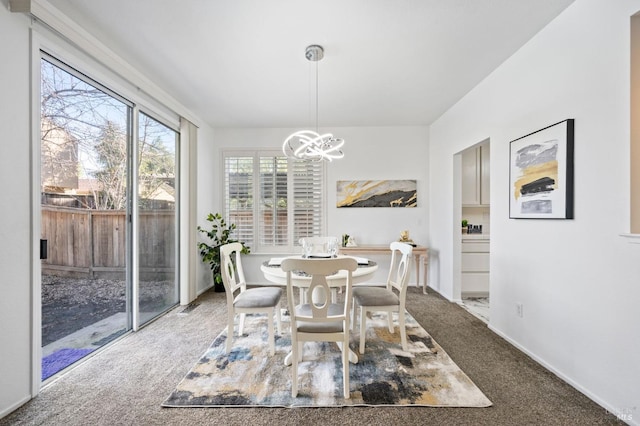 carpeted dining area with baseboards and a notable chandelier