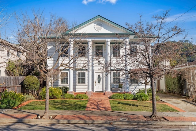 neoclassical home with a front yard and fence