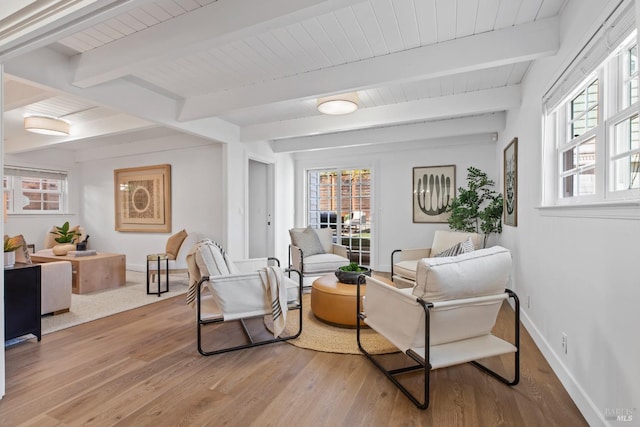 sitting room with light wood-type flooring, wood ceiling, baseboards, and beamed ceiling