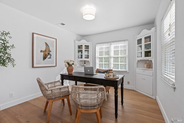 home office featuring baseboards, visible vents, and light wood finished floors