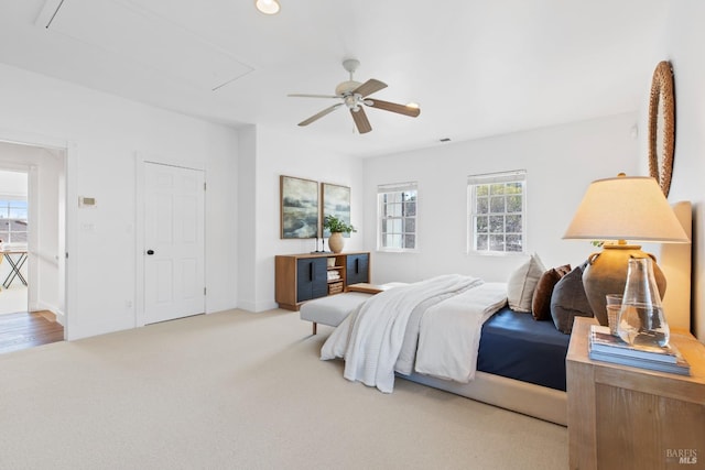 carpeted bedroom with attic access, ceiling fan, and baseboards