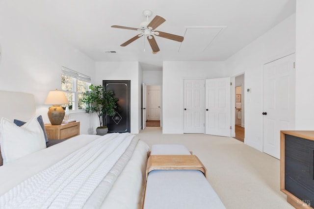 carpeted bedroom with attic access, visible vents, ceiling fan, and multiple closets