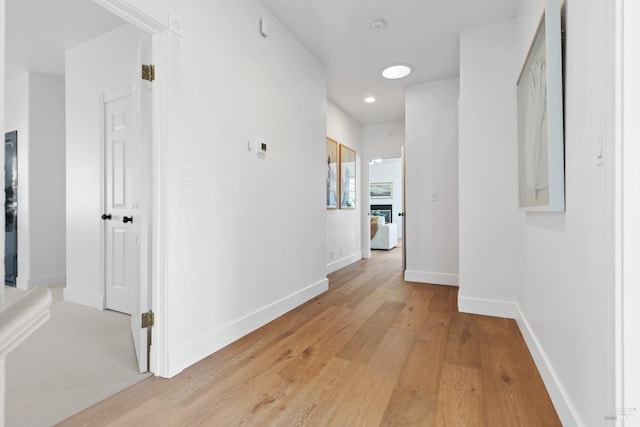 corridor featuring baseboards and light wood finished floors