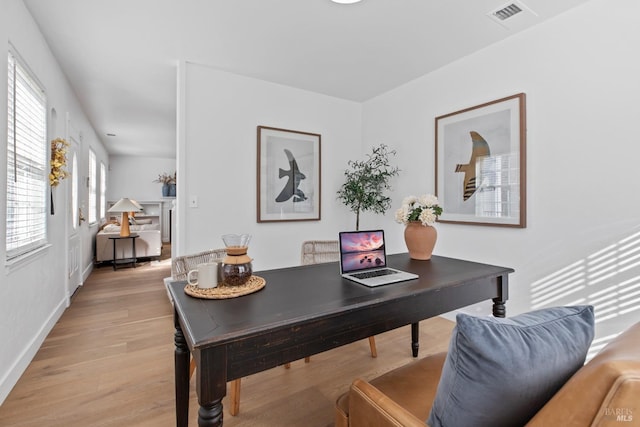 office space featuring baseboards, visible vents, and light wood finished floors