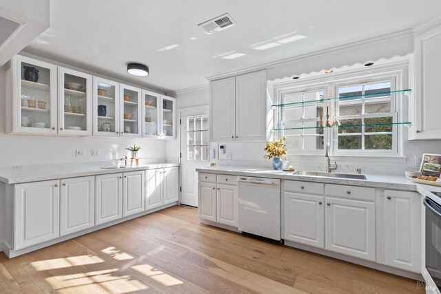 kitchen featuring white dishwasher, a sink, visible vents, white cabinets, and light wood finished floors