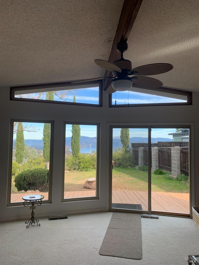 entryway with lofted ceiling with beams, carpet, and a textured ceiling