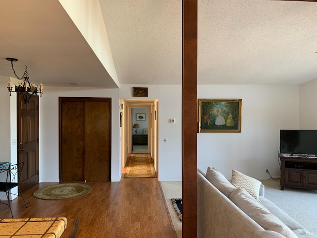 living room with lofted ceiling, hardwood / wood-style floors, a textured ceiling, and a chandelier