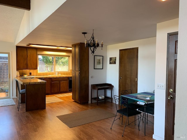 kitchen featuring vaulted ceiling, a breakfast bar, tasteful backsplash, kitchen peninsula, and light wood-type flooring