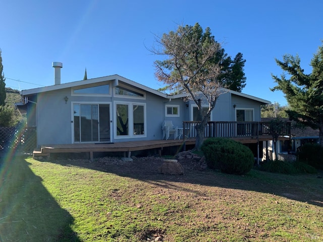 back of property with a wooden deck and a lawn