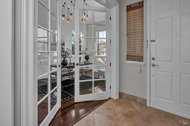 doorway with french doors, an inviting chandelier, and light tile patterned flooring