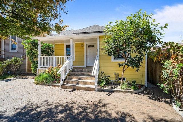 view of front of home featuring covered porch and a shingled roof