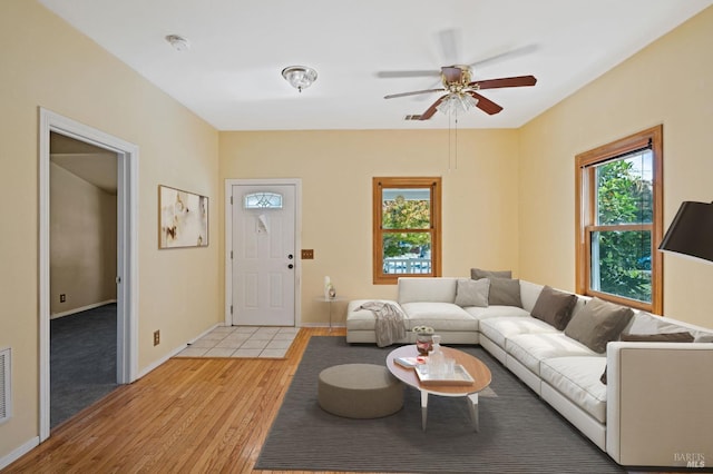living room featuring ceiling fan, baseboards, visible vents, and light wood finished floors